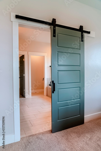 Sliding gray wooden panel door that leads to the bathroom of a home