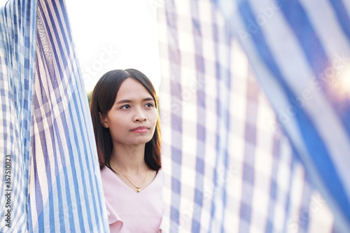 Asian woman is at the gap in a fabric that has the light from the sun. Free Download Asian woman is at the gap in a fabric that has the light from the sun. - GFXLoad