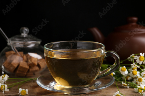 Delicious chamomile tea in glass cup on wooden table