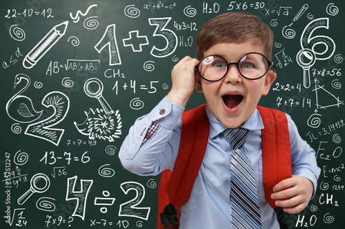 Schilderij op canvas Funny little child wearing glasses near chalkboard with mathematical equations