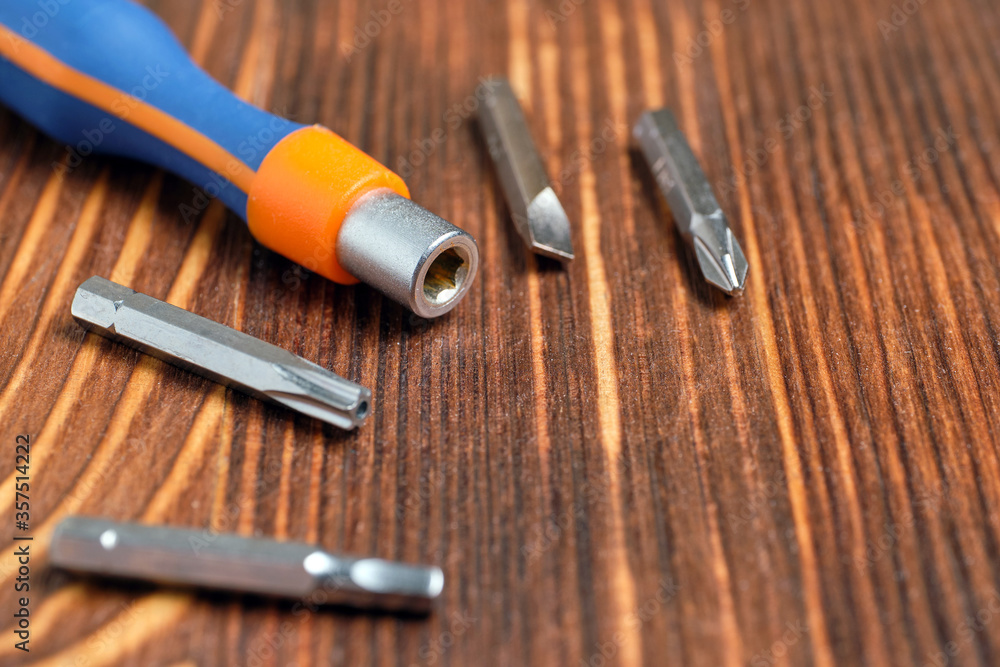 Screwdriver with interchangeable nozzles on a wooden background. Screwdriver with interchangeable nozzles on a wooden background.