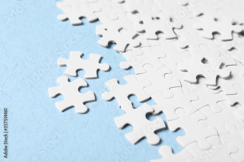 Blank white puzzle pieces on light blue background