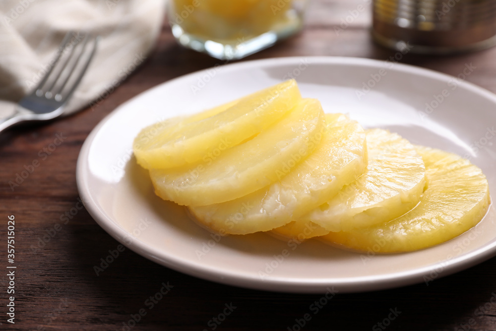 Tasty canned pineapple slices on wooden table, closeup