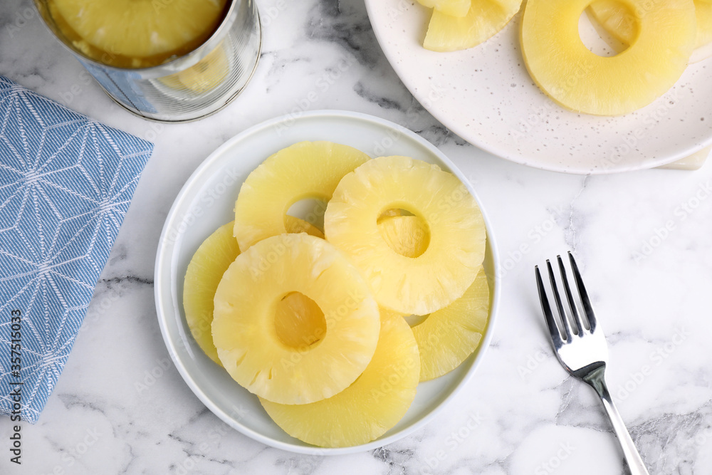 Flat lay composition with canned pineapple pieces on white wooden table