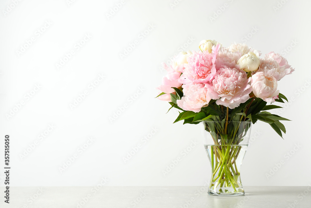 Beautiful peony bouquet in vase on table against white background. Space for text Beautiful peony bouquet in vase on table against white background. Space for text