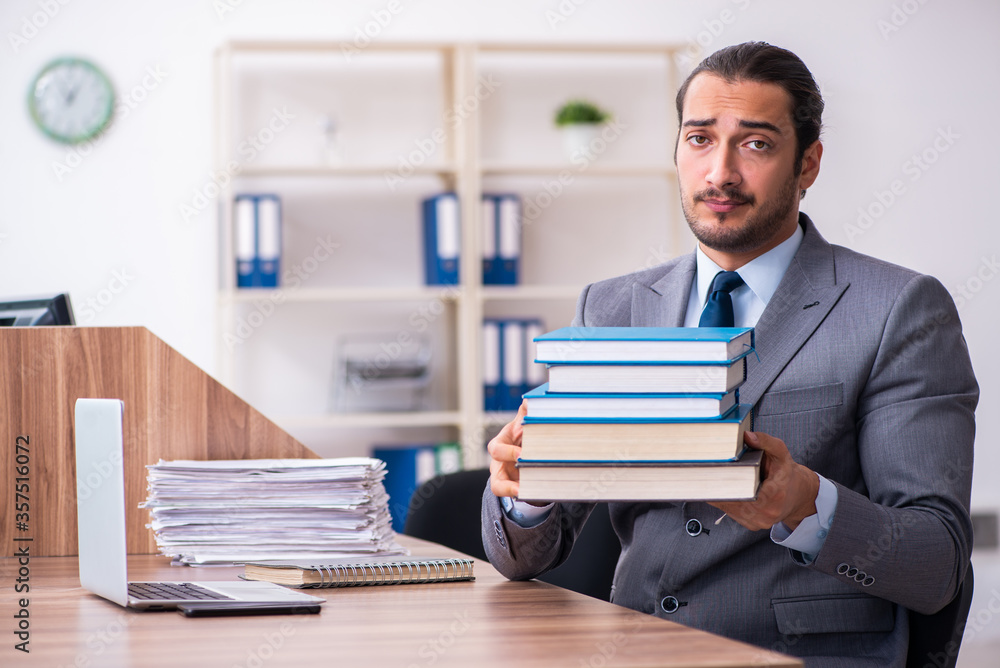Young male businessman reading books at workplace Young male businessman reading books at workplace