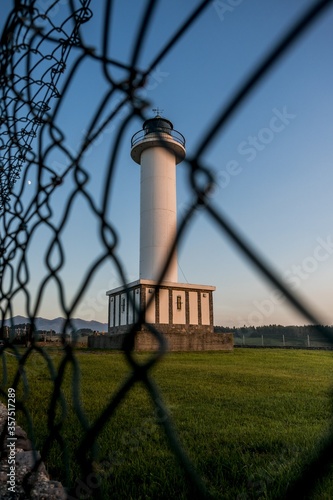 Lighthouse of Lastres with the fence on the foreground captured in the town of Luces, Spain photo