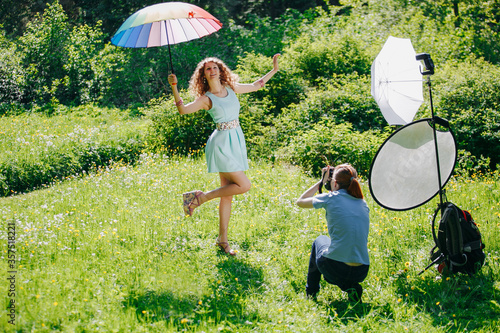 Backstage of a professional photo shoot in nature. Photosession of the model on the open air. Beautiful emotional girl posing in front of the camera. Woman ..photographer takes pictures