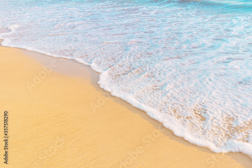 Sandy beach and sea wave in warm sunset light. Tropical shore background with copy space