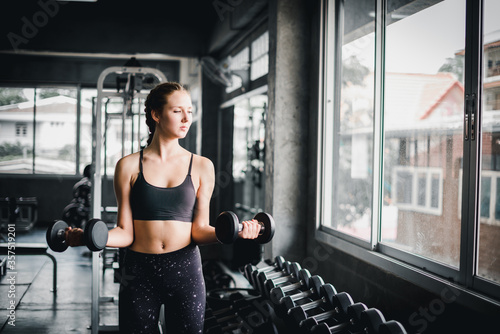 Beautiful female athletes are exercising in the gym. By lifting the dumbbell. The gym has a full range of exercise equipment.