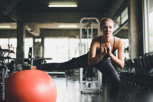 A beautiful woman wearing a sports shirt, stretching and relaxing with a rubber ball, yoga or exercise ball.