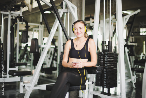 Beautiful women come to exercise in the gym and are relaxed by listening to music from headphones. She wears a sportswear.