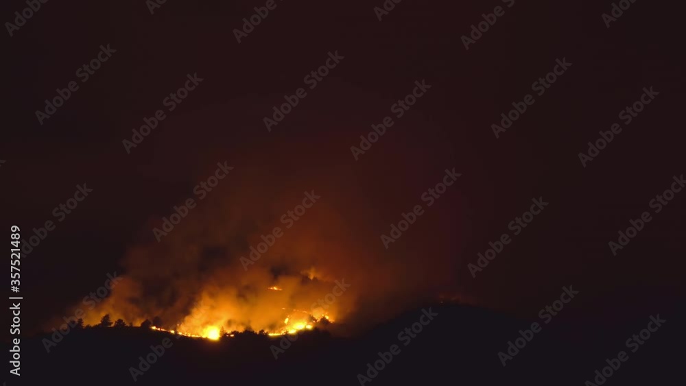 A forrest fire burning the top of a mountain at night with high flames glowing the dark sky A forrest fire burning the top of a mountain at night with high flames glowing the dark sky