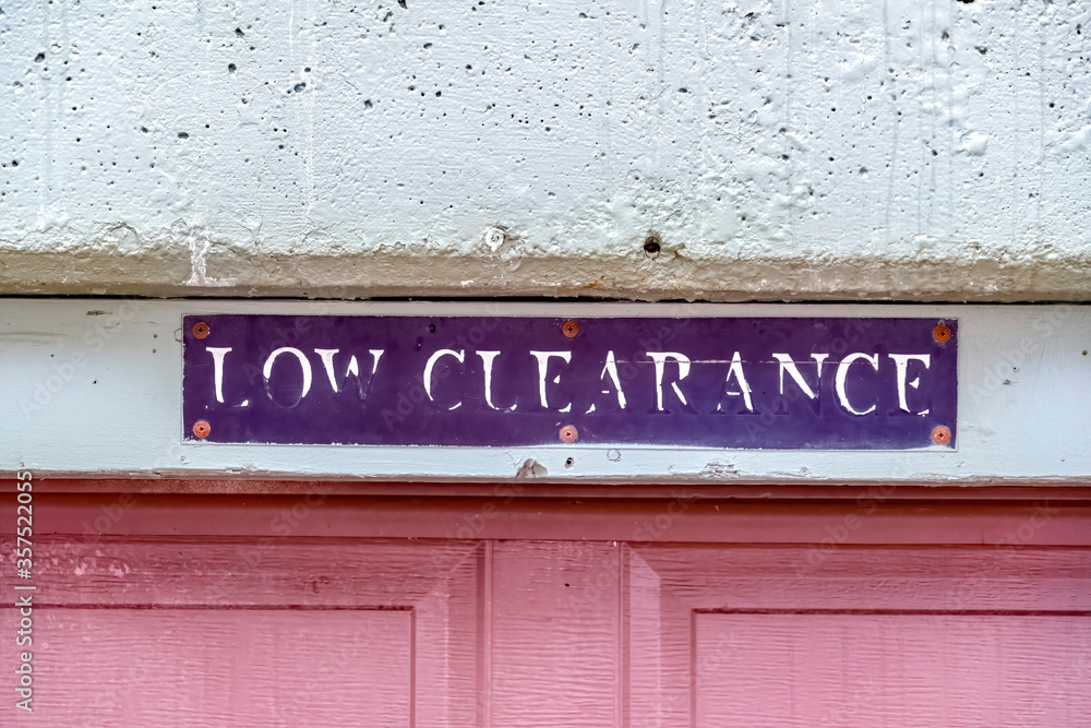 Low Clearance sign above the panelled red wooden garage door of a building