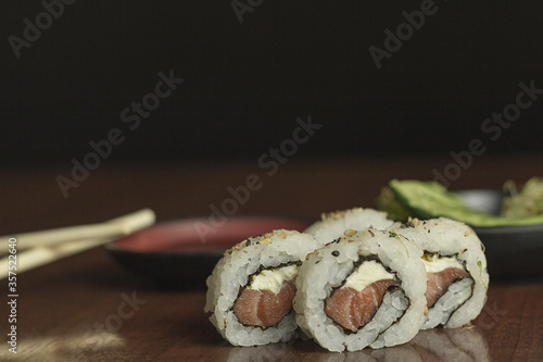 Sushi uramaki com salmão cru e cream cheese acompanhado de shoyu, salada de pepino e broto de feijão