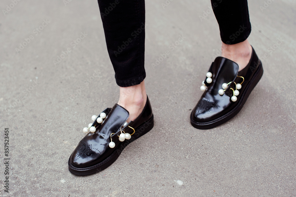 Fashion woman wearing black jeans and fashionable black leather shoes with pearls. Street style . Fashion woman wearing black jeans and fashionable black leather shoes with pearls. Street style .