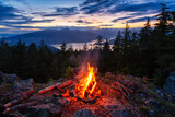 Warm Camp Fire on top of a mountain with Beautiful Canadian Nature Landscape in background during a colorful Sunset. Taken on Bowen Island, near Vancouver, British Columbia, Canada.