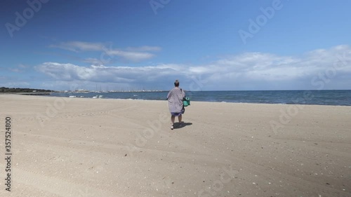 Woman wearing kimono walking towards sea on Hampton bay beach, Melbourne Australia, day time sunny, Wide shot photo