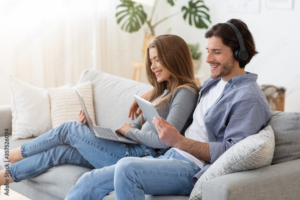 Couple sitting on couch at home and using gadgets Couple sitting on couch at home and using gadgets