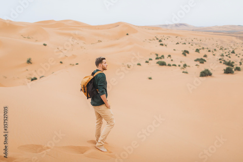Man backpacker travel in Morocco  Sahara desert. Explore african nature  sand dunes around. Freedom and lifestyle concept.