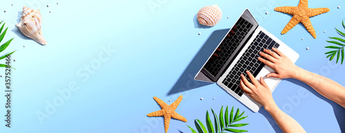 Canvas Print Person using a laptop computer with summer theme objects - flat lay