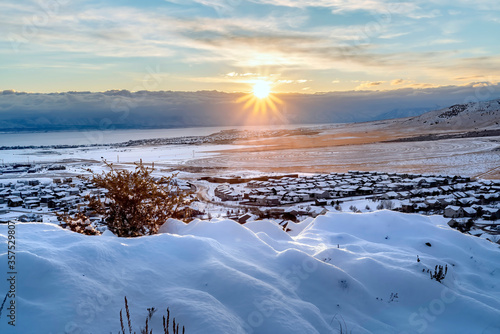 Snowed in hill overlooking frosted houses and lake in Draper Utah in winter