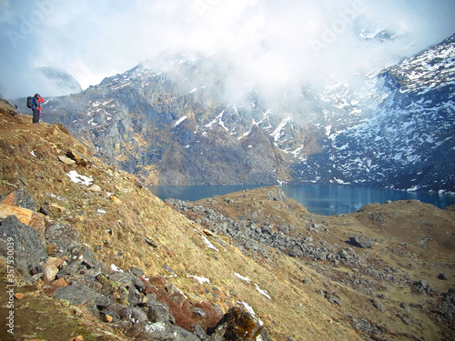 Trekker at Gosainkunda lake, looking outwards to the mountains. Nepal Langtang National Park. Concept: looking forward; positive outlook; embrace the unknown; embrace the future; facing the world photo