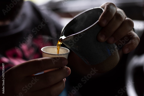 man pouring coffee on a cup of coffee inside car