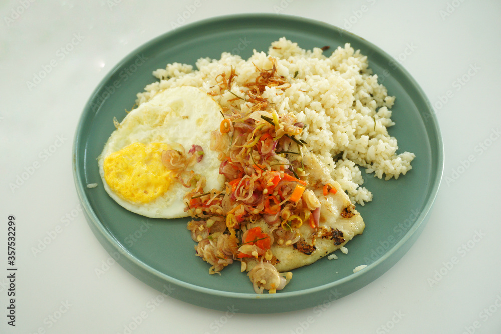 Fried rice and egg with grilled dory fish with chilli topping on a green plate. Fried rice and egg with grilled dory fish with chilli topping on a green plate.