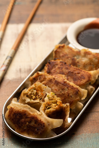 gyoza on silver plate wooden table chopsticks and soy sauce