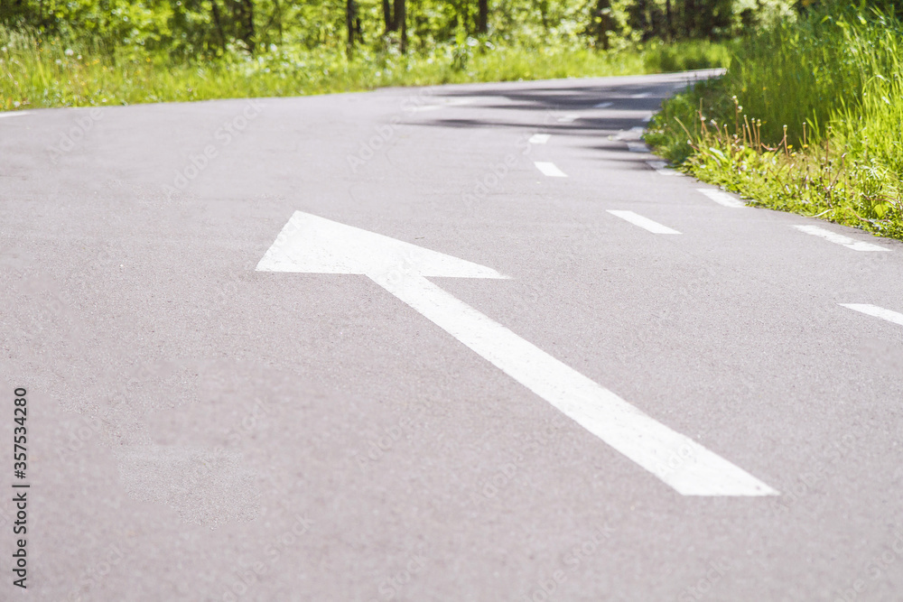 Obraz premium White forward arrow on running track. Asphalt walk way in park. Stock photography.