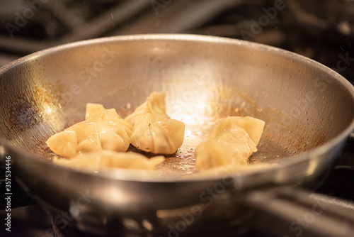 chef preparing asian gyoza on oven and pan with water photo