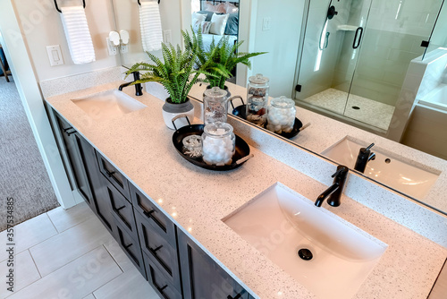 Photos Two sinks with black faucet on white countertop over cabinets on tile floor