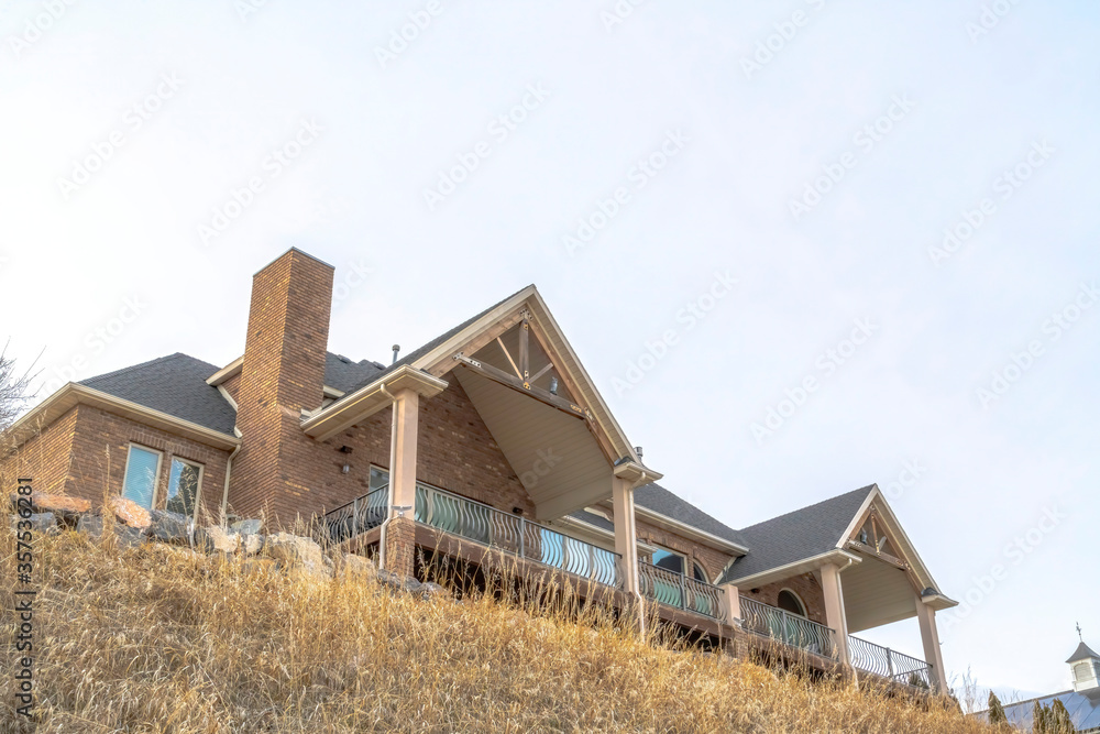 Hill top home exterior featuring stone brick wall and gable roofs over balcony Hill top home exterior featuring stone brick wall and gable roofs over balcony