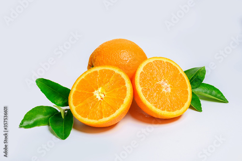 Two fresh orange slices and one orange fruit with green leaf isolated on white background.