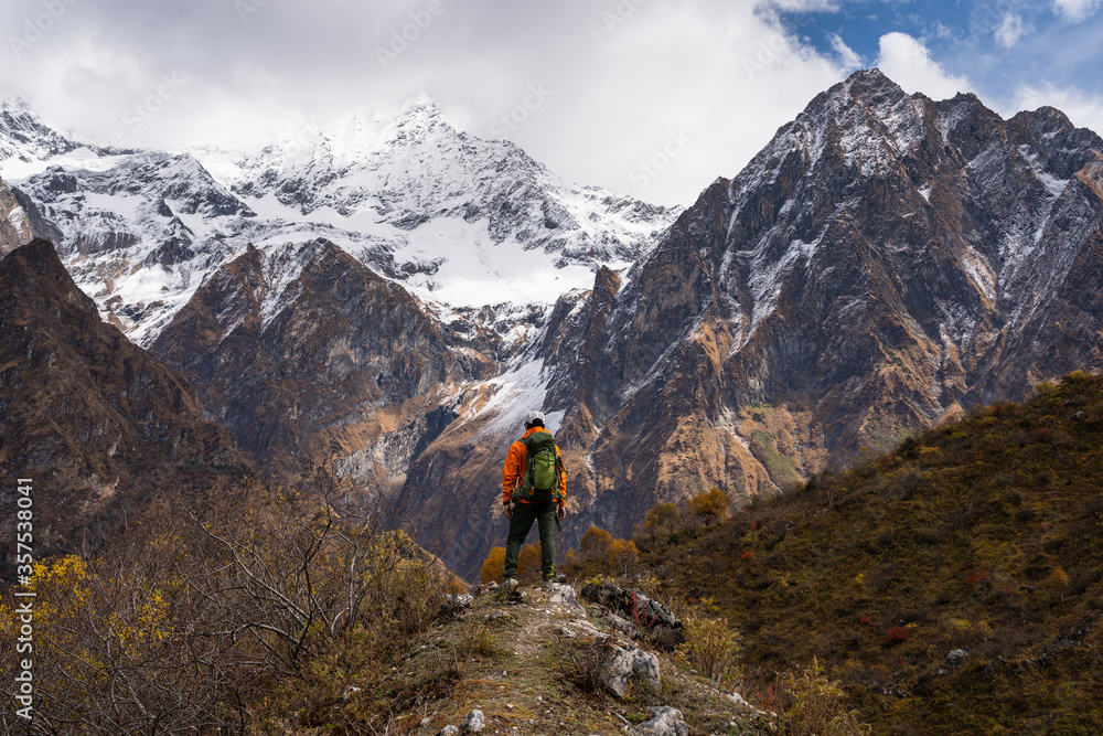 Young trekker standing on top of the hill and looking to snow Himalaya mountains range in Manaslu circuit trekking route in Himalaya mountains, Nepal