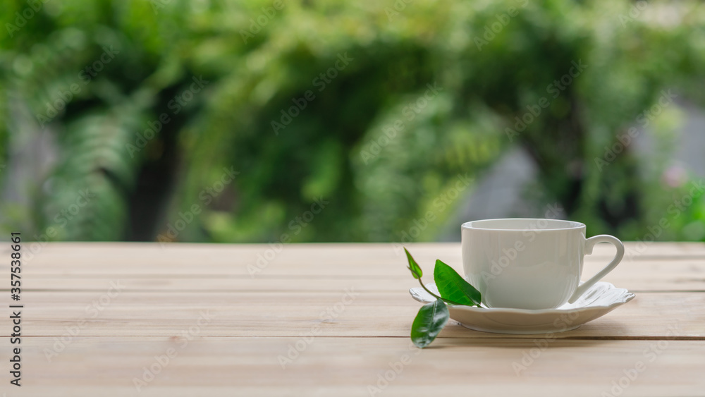 cup of tea with fresh tea leaves on wooden table with green nature blurred background cup of tea with fresh tea leaves on wooden table with green nature blurred background
