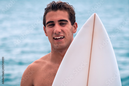 Young surfer with white surfboard smililg portrait