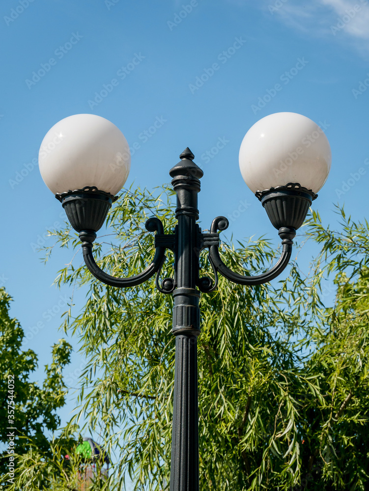 Detail of a street lamp or lamp post with two white globes against ble sky. Detail of a street lamp or lamp post with two white globes against ble sky.