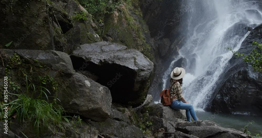 Woman go hiking and look at the waterfall in forest Woman go hiking and look at the waterfall in forest