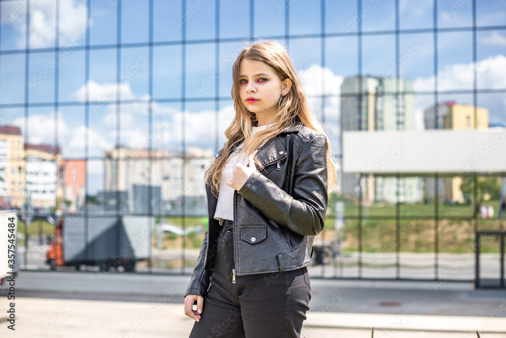 young brunette schoolgirl with bright makeup in black leather jacket posing in the parking lot young brunette schoolgirl with bright makeup in black leather jacket posing in the parking lot