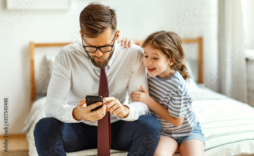 Busy father using smartphone near playful daughter. photo