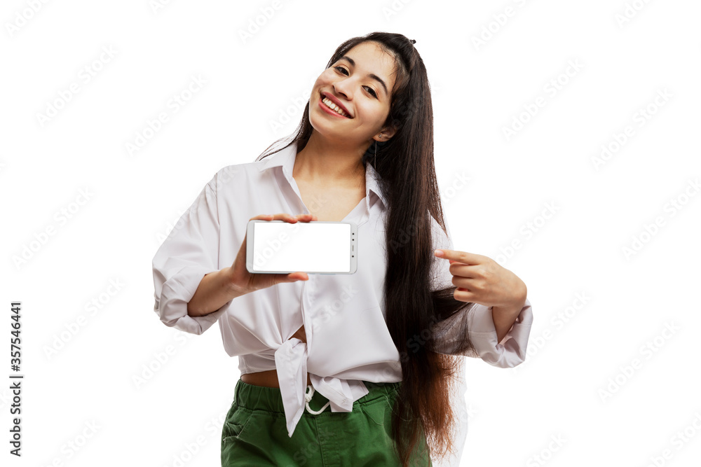 Smiling young girl shows on an isolated screen phone. Brunette with long hair. Isolated on a white background. Smiling young girl shows on an isolated screen phone. Brunette with long hair. Isolated on a white background.