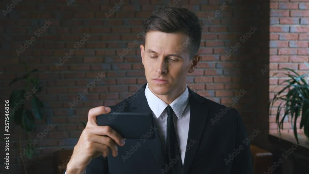 Young man is watching an unpleasant video on a smartphone. Businessman is unpleasantly shocked by what he saw on the mobile phone. Aversion of content. Young man is watching an unpleasant video on a smartphone. Businessman is unpleasantly shocked by what he saw on the mobile phone. Aversion of content.