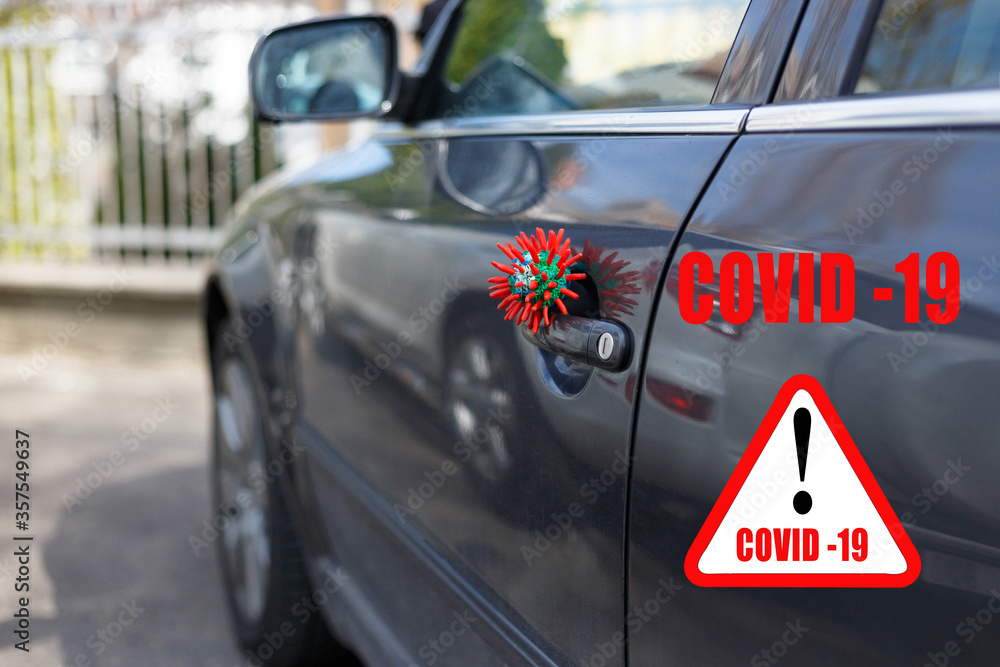 Attention about spread of Coronavirus COVID-19. Red headline with inscription COVID-19 on white triangle with abstract virus strain model sitting on the door of vehicle. Attention about spread of Coronavirus COVID-19. Red headline with inscription COVID-19 on white triangle with abstract virus strain model sitting on the door of vehicle.