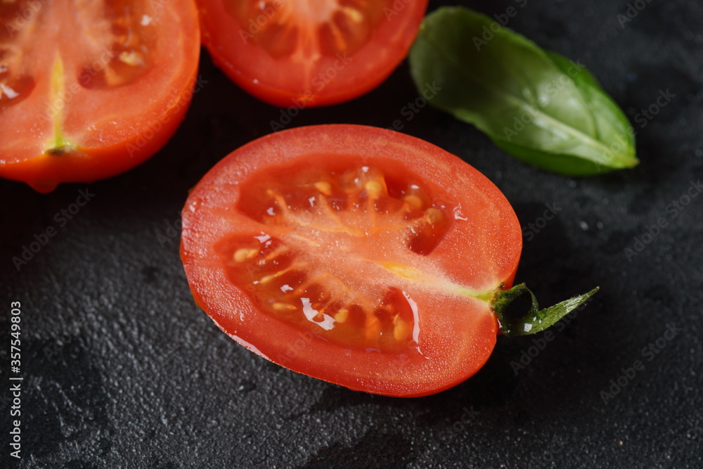 Pieces of cut fresh tomatoes over dark background.
Tomato with droplets of water with basil leaves. Close up Pieces of cut fresh tomatoes over dark background.
Tomato with droplets of water with basil leaves. Close up