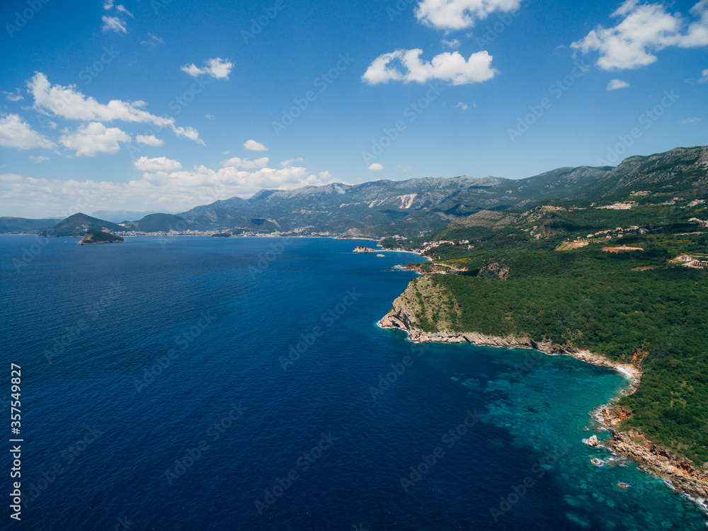 The colorful coast of Montenegro. Blue sky with small white clouds, above the blue Adriatic Sea.