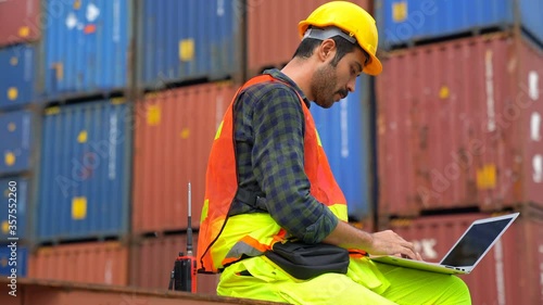 Foreman using laptop computer check Container loading real time monitoring system from cargo freight ship for import export. Logistic, Transportation concept. 