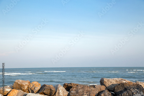 The rocky beach with the sea and blue sky.