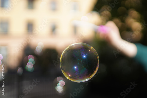 Soap bubble in the air. Girl makes soap bubbles with a stick in her hand.